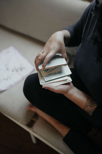 therapist with tattoos holding tarot cards